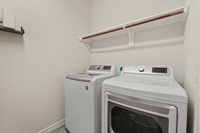 washroom featuring washer and dryer, laundry area, and baseboards