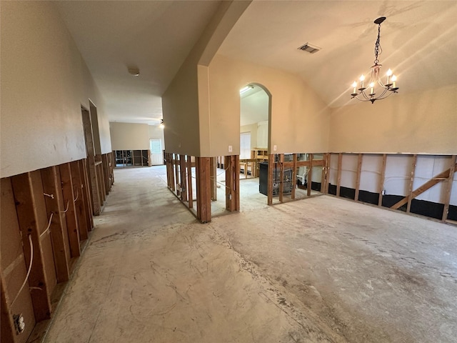 miscellaneous room featuring visible vents, concrete flooring, vaulted ceiling, arched walkways, and a notable chandelier