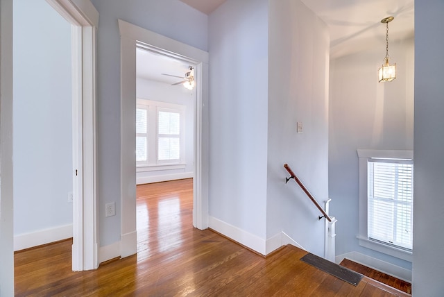 hall with a wealth of natural light, baseboards, an upstairs landing, and wood finished floors