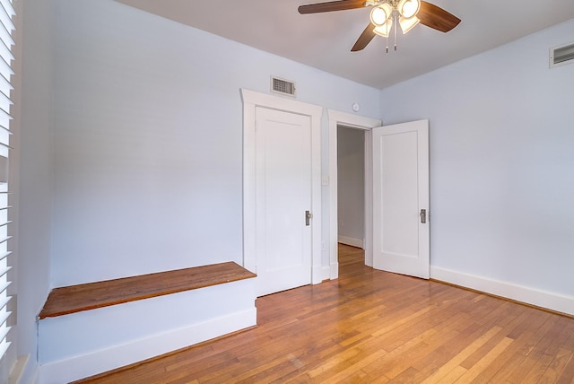 empty room featuring visible vents, ceiling fan, baseboards, and light wood-style floors