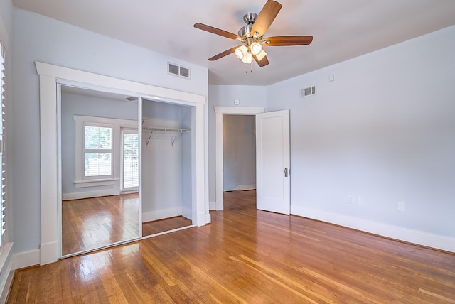 unfurnished bedroom with a closet, visible vents, baseboards, and wood-type flooring