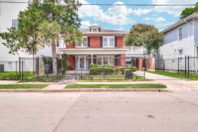 traditional style home with brick siding, covered porch, and a fenced front yard