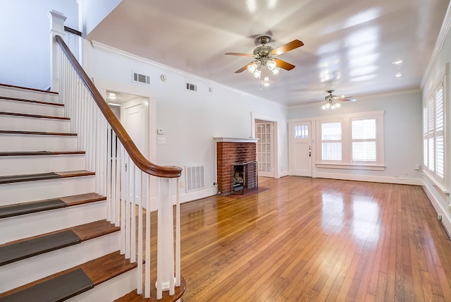 unfurnished living room featuring hardwood / wood-style floors, stairs, baseboards, and visible vents