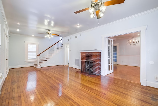 unfurnished living room featuring baseboards, visible vents, light wood-style flooring, stairs, and crown molding