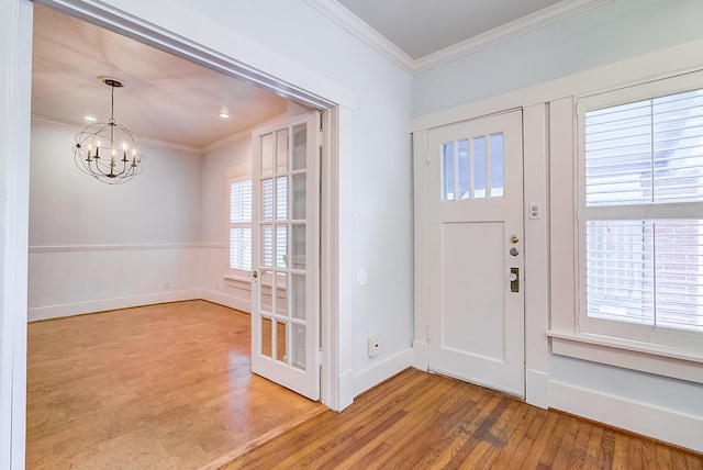 entrance foyer featuring baseboards, a notable chandelier, wood finished floors, and crown molding