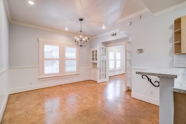 unfurnished dining area with an inviting chandelier, baseboards, visible vents, and ornamental molding