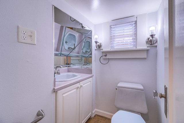 half bath featuring toilet, vanity, and baseboards