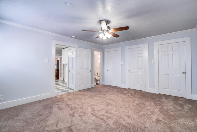 unfurnished bedroom featuring two closets, ornamental molding, connected bathroom, carpet, and baseboards