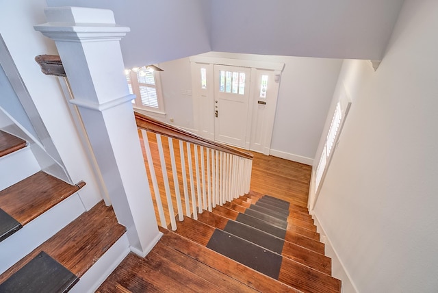 stairway with lofted ceiling, wood finished floors, and baseboards