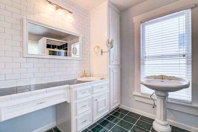 full bath featuring tile patterned floors, baseboards, tasteful backsplash, and a sink