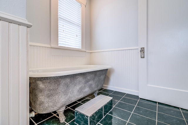 full bathroom featuring tile patterned flooring, wainscoting, and a bath