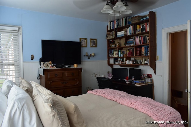 bedroom with a wainscoted wall and ceiling fan