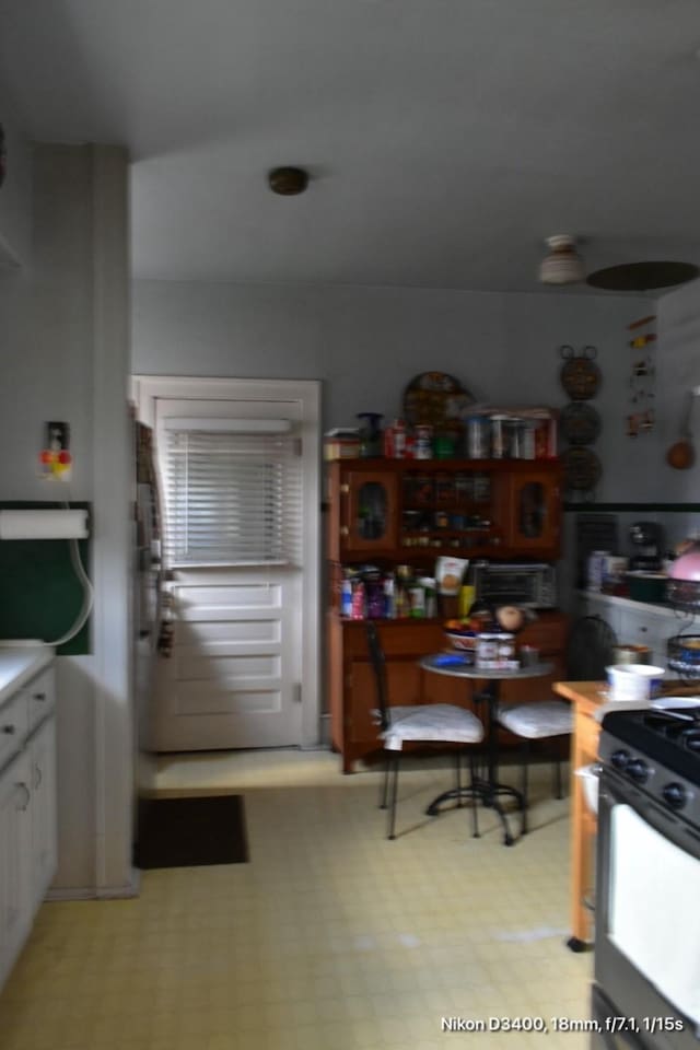 kitchen featuring stove, light floors, and white cabinets