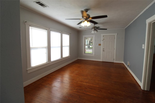 empty room featuring visible vents, baseboards, ornamental molding, a ceiling fan, and wood-type flooring