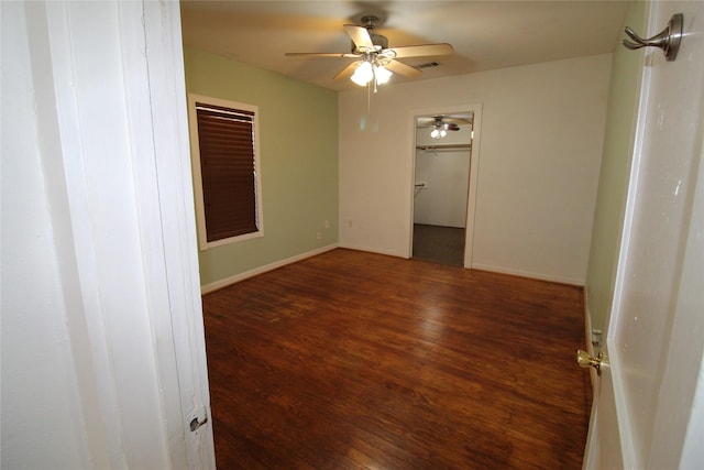 empty room with visible vents, a ceiling fan, baseboards, and wood finished floors