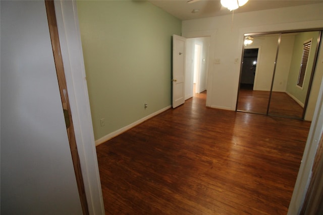 unfurnished bedroom with wood finished floors, baseboards, and a closet