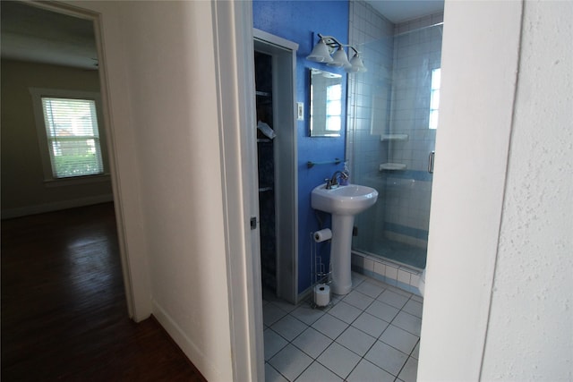 bathroom with a sink, baseboards, a shower stall, and tile patterned floors