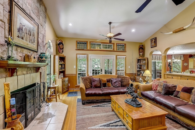 living area with light wood finished floors, a fireplace, arched walkways, ceiling fan, and wainscoting