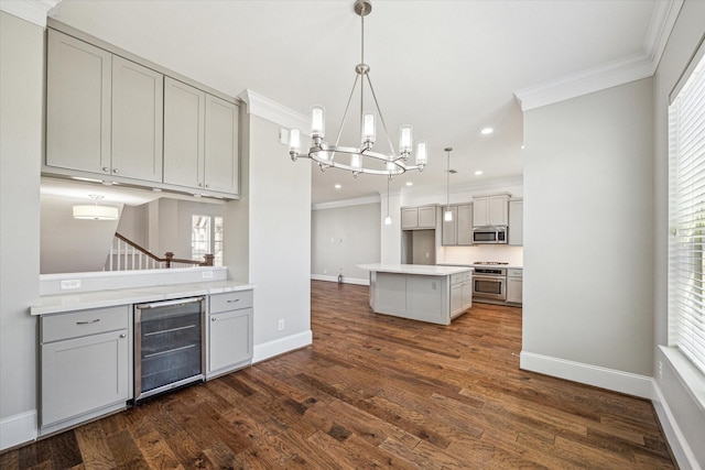 kitchen featuring gray cabinetry, beverage cooler, ornamental molding, stainless steel microwave, and stove