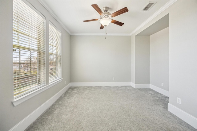 carpeted empty room featuring ceiling fan, baseboards, visible vents, and ornamental molding