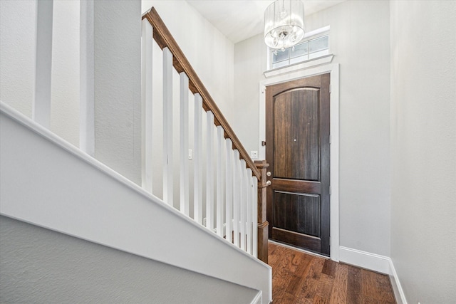 entryway with baseboards, a notable chandelier, wood finished floors, and stairs