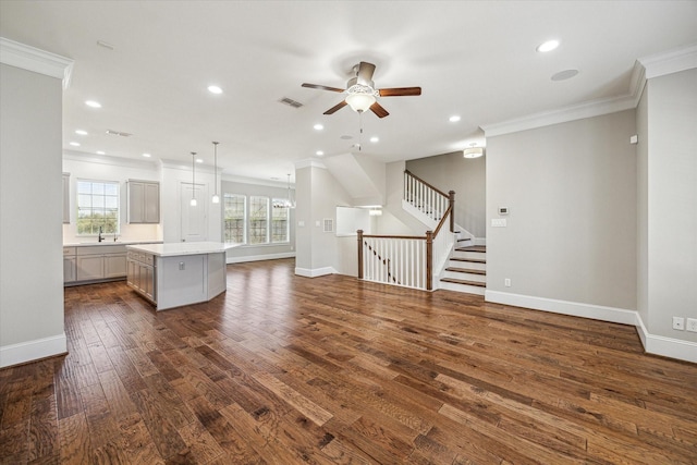 unfurnished living room featuring visible vents, dark wood-type flooring, baseboards, stairs, and ornamental molding