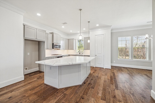 kitchen featuring a kitchen island, dark wood-style flooring, a sink, ornamental molding, and appliances with stainless steel finishes