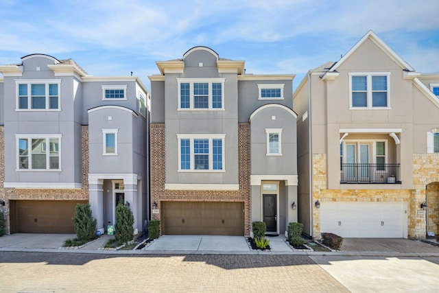 view of property with driveway, an attached garage, stucco siding, stone siding, and brick siding