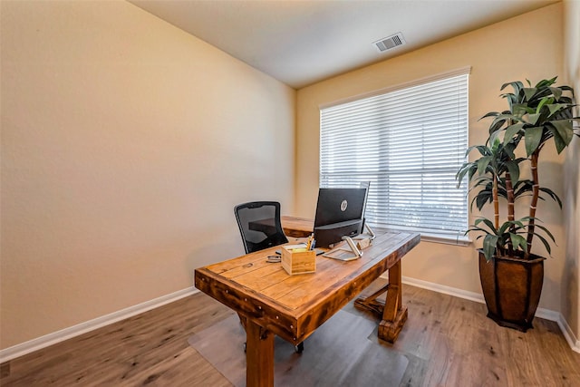 office area with wood finished floors, visible vents, and baseboards