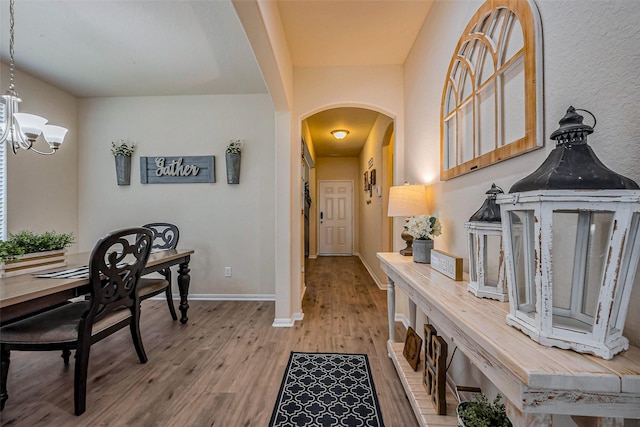 interior space featuring an inviting chandelier, wood finished floors, arched walkways, and baseboards