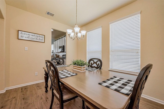 dining room featuring visible vents, baseboards, an inviting chandelier, and wood finished floors