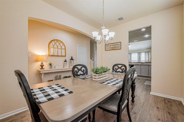 dining area with wood finished floors, visible vents, a chandelier, and baseboards