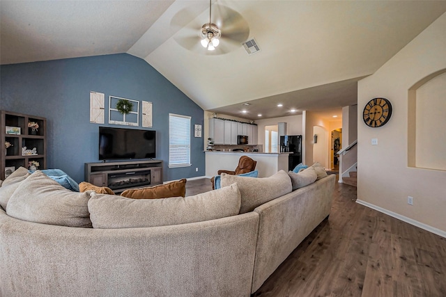 living area featuring dark wood finished floors, visible vents, arched walkways, and lofted ceiling