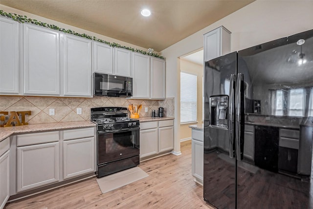 kitchen featuring black appliances, light wood-style flooring, light stone counters, recessed lighting, and decorative backsplash