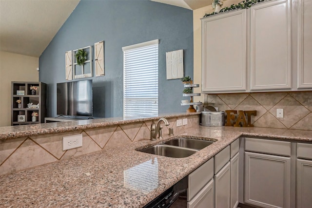 kitchen with light stone countertops, vaulted ceiling, decorative backsplash, plenty of natural light, and a sink