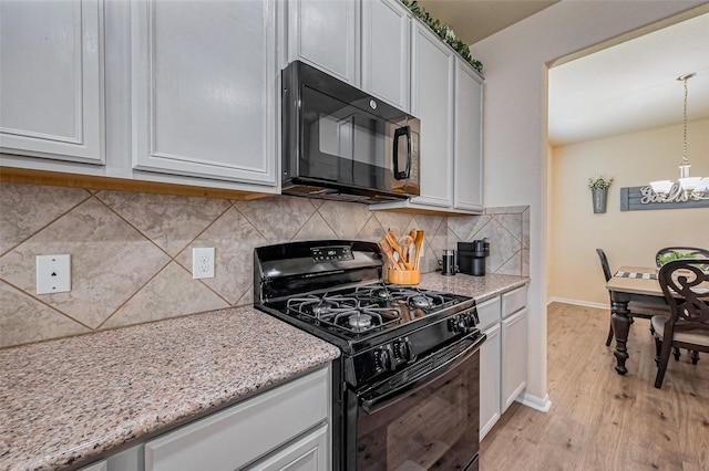 kitchen featuring light stone countertops, decorative backsplash, light wood-style flooring, an inviting chandelier, and black appliances