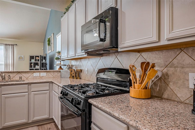 kitchen with a sink, tasteful backsplash, black appliances, and a peninsula