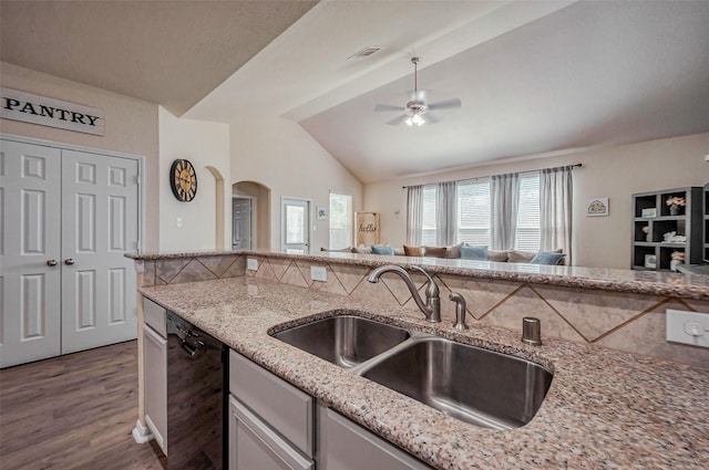 kitchen with visible vents, light stone countertops, lofted ceiling, black dishwasher, and a sink