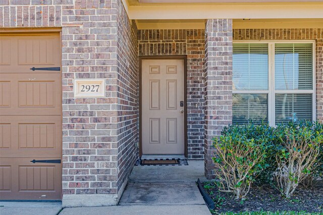 doorway to property featuring brick siding and an attached garage