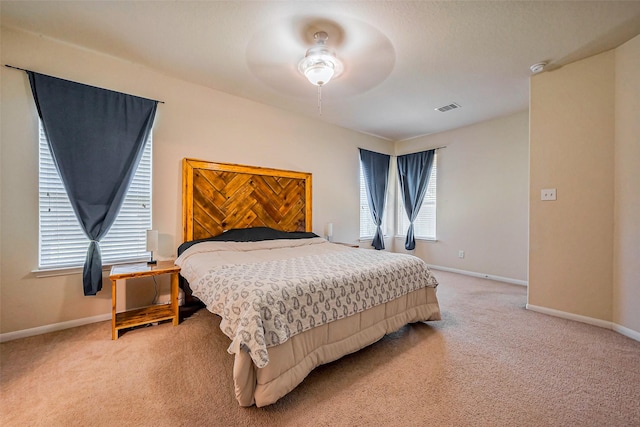 bedroom featuring visible vents, light colored carpet, a ceiling fan, and baseboards