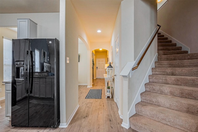 interior space featuring arched walkways, baseboards, and wood finished floors