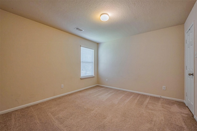 spare room with visible vents, baseboards, light colored carpet, and a textured ceiling