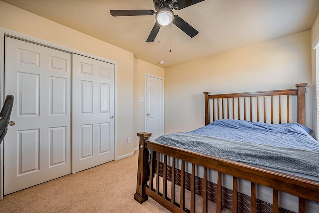 bedroom with a closet, baseboards, light colored carpet, and ceiling fan