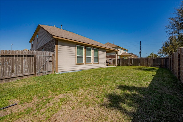 rear view of house with a fenced backyard, brick siding, and a yard