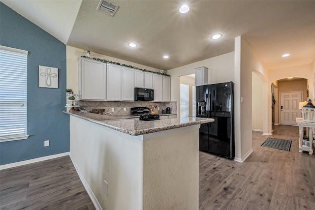 kitchen featuring light wood-type flooring, decorative backsplash, a peninsula, arched walkways, and black appliances