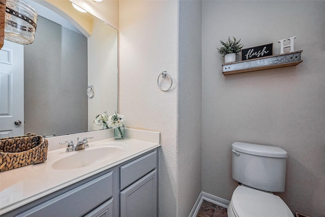 half bath with baseboards, toilet, and vanity