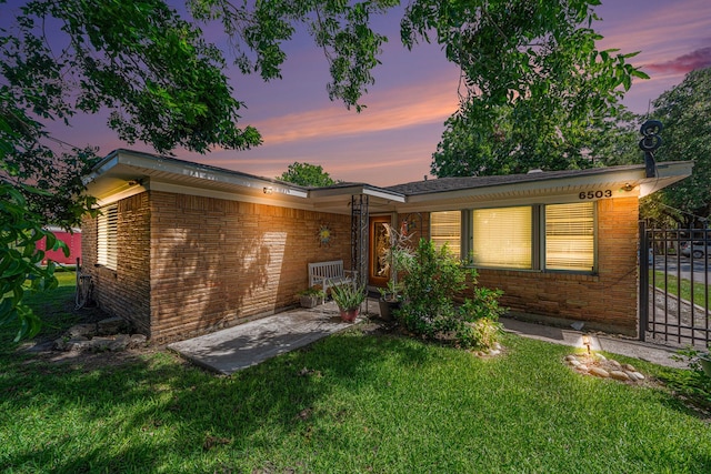 view of front of home with brick siding and a lawn