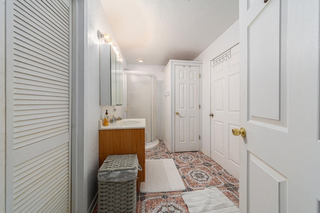 full bath featuring a closet, a shower stall, a textured ceiling, and vanity