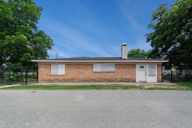 view of front of house with brick siding, a chimney, and fence