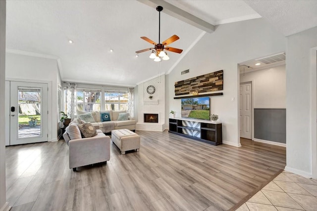 living area with visible vents, high vaulted ceiling, a fireplace, light wood-style floors, and beamed ceiling